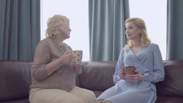 Yaşlı bir kadın genç bir kadınla konuşuyor, elinde çay, huzurevi, bakım... — Stok video