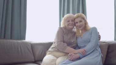 Sevgi dolu bir anne-kız kucaklaşması, kameraya bakmak, aile bağı.