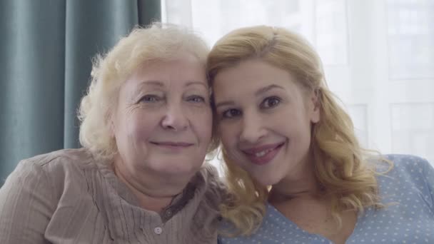 Attractive woman kissing mother's cheek, looking at camera, unconditional love — Stock Video