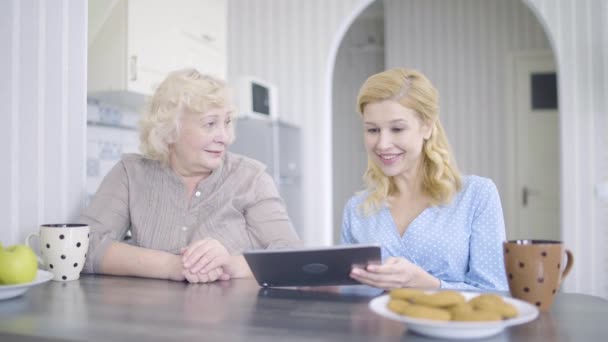 Ευτυχισμένη νεαρή γυναίκα και μητέρα βλέποντας φωτογραφίες στο tablet, αγοράζοντας ρούχα σε απευθείας σύνδεση — Αρχείο Βίντεο