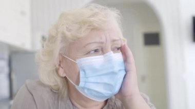 Koruyucu maskeli depresif bir kadın kötü haberleri dinliyor, tehlikeli bir virüs.