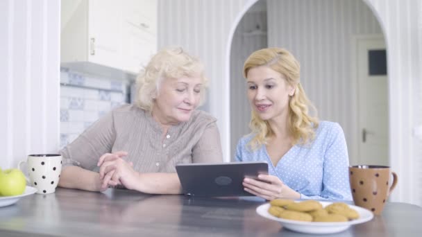 Madre e hija mayores de compras en línea, discutir fotos en la tableta, diversión — Vídeo de stock