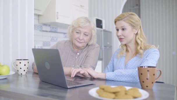 Giovane donna e madre guardando lo schermo del computer portatile, discutendo foto, app di prenotazione — Video Stock