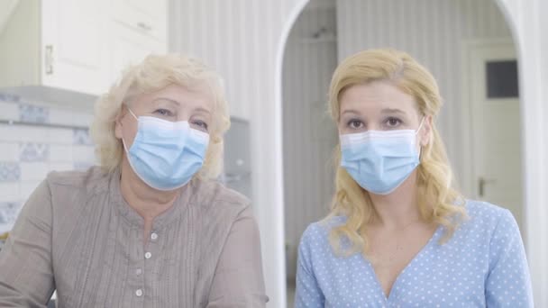 Mujeres tristes con máscaras mirando a la cámara, brote de coronavirus, enfermedad peligrosa — Vídeos de Stock