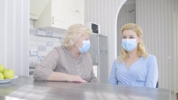 Мать в маске утешительная дочь, трудности коронавирусного карантина — стоковое видео