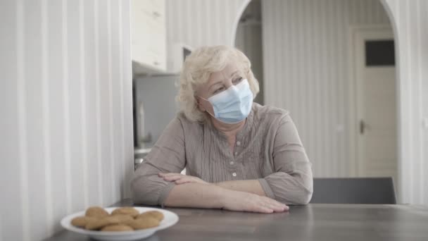 Triste anciana en máscara protectora pensando en el problema en casa, sintiéndose sola — Vídeos de Stock