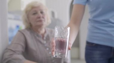 Hasta yaşlı kadına bir bardak su servis eden nazik gönüllü, bakımevi bakımı.
