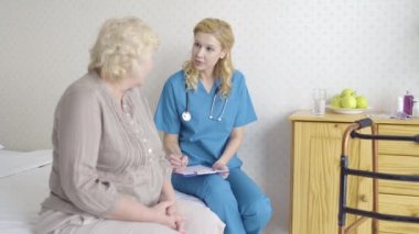 Kadın doktor yaşlı bir hastayla konuşuyor reçete yazıyor, sağlık sigortası...