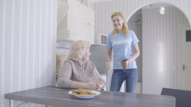 Fille bénévole prenant soin de dame à la retraite dans la cuisine, aide caritative aux personnes âgées — Video