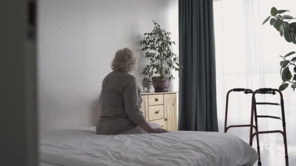 Behinderte alte Frau sitzt allein im Zimmer, nimmt Medikamente, im Alter einsam — Stockvideo