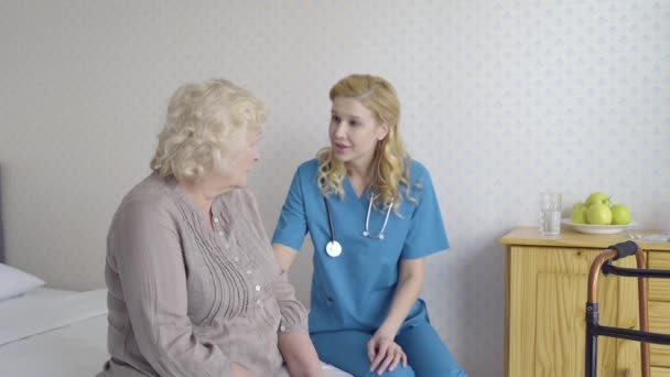 Nazik hemşire üzgün yaşlı kadınla konuşuyor, yaşlı insanlara psikolojik yardım yapıyor. — Stok video