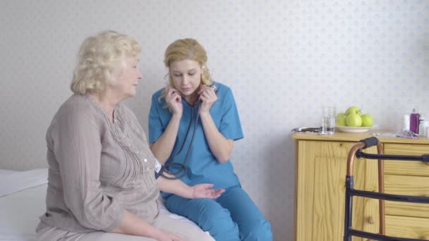 Arzt misst Blutdruck, untersucht Seniorin zu Hause, Gesundheitswesen — Stockvideo