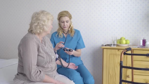 Kadın doktor huzurevindeki yaşlı bayanı muayene ediyor, sağlık hizmetleri, bakım... — Stok video