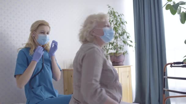 Femme médecin examinant la patiente contagieuse dans un masque de protection, soins de santé — Video