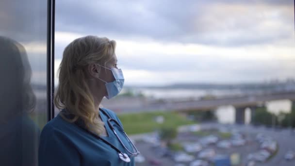 Εξαντλημένη γυναίκα γιατρός σε προστατευτική μάσκα κοιτάζοντας το αστικό τοπίο, επιδημία — Αρχείο Βίντεο