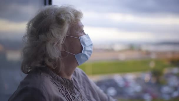 Femme âgée portant un masque protecteur, regardant la ville, enfermement épidémique — Video
