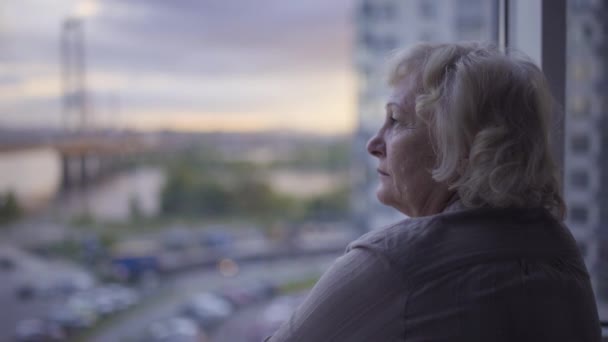 Pencereden bakan bunalımlı yaşlı kadın, üzücü anılar, yaşlı yalnızlık. — Stok video