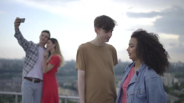 Молодой человек разговаривает с женщиной на открытом воздухе, первое свидание, отношения в половом созревании, веселье — стоковое видео