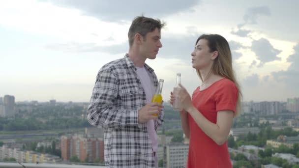 Szczęśliwi przyjaciele brzęczą butelkami, piją orzeźwiający napój na świeżym powietrzu, imprezują — Wideo stockowe