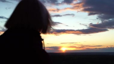 Gün batımında kadın silueti, gün batımını izleyen genç bir kadın, üzüntü.