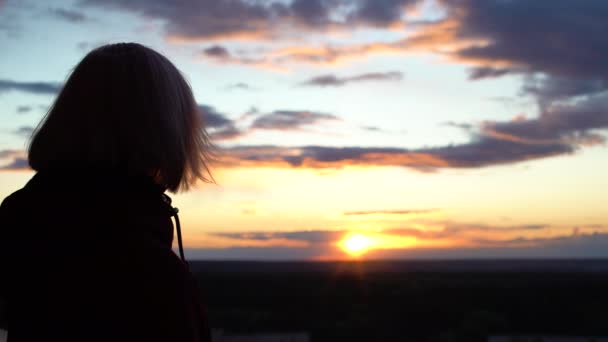 Mujer joven mirando atardecer, pelo ondeando en el viento, libertad, contemplación — Vídeo de stock