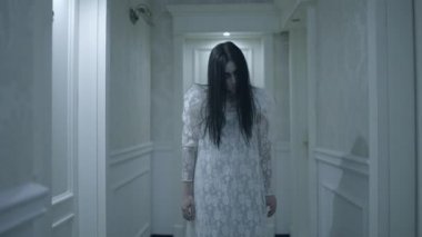 Ele geçirilmiş kadın korkunç hareketler yapıyor, çılgın gözlerle kameraya bakıyor.