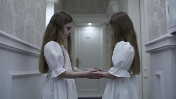 Deadly pale evil twins playing hand game in abandoned house hall, staring at cam — Stock Video