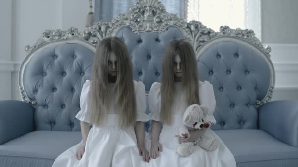 Zombie gemelos mirando cam, caras ocultas en el pelo, sosteniendo terrible sangriento juguete — Vídeos de Stock