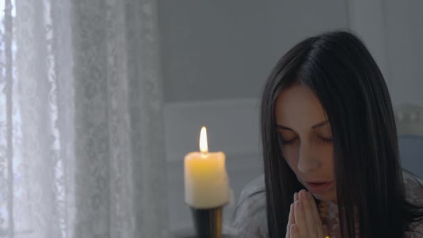 Jonge vrouw bidt voor kaars, vraagt om hulp, religieus ritueel, hoop — Stockvideo