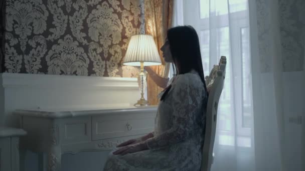 Зачарованная женщина в свадебном платье сидит на стуле в отеле, дух леди — стоковое видео