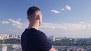 Kendine güvenen genç adam çatıdan şehre bakıyor, başarılı lider, gururlu.