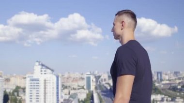 Mutlu erkek, evet işareti yapıyor, çatıda duruyor, amacına ulaşıyor, güç kazanıyor.