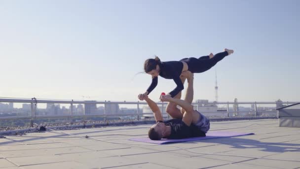 Novio y novia haciendo acroyoga en la azotea, practicando pose de pájaro delantero — Vídeos de Stock