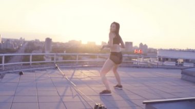 Brunette woman moving hips and butt, dancing twerk on the roof top, flirting