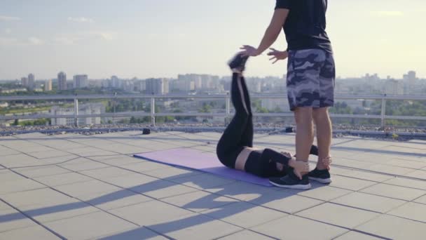 Vrouwelijke atleet doet abdominale oefening, man assisteren vrouw tijdens de training — Stockvideo