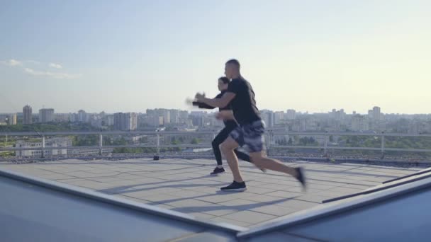 Jonge actieve mensen springen op het dak, gesynchroniseerde crossfit training — Stockvideo