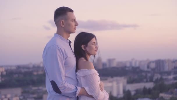 Нежная пара молодых влюбленных обнимается, наслаждается городским пейзажем, романтическое свидание на крыше — стоковое видео