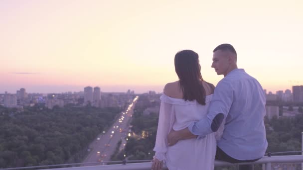 Молодой человек и влюбленная женщина любовались вечерним городским пейзажем с крыши, сладкое свидание — стоковое видео
