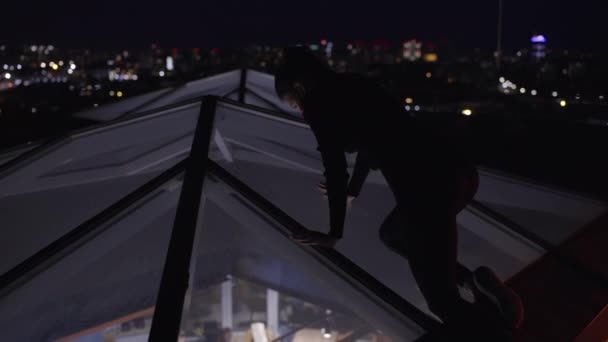 Подозрительная женщина в черном костюме шпионит за офисом через стеклянную крышу, планируя преступление. — стоковое видео