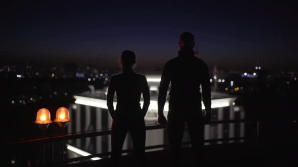 Silhouettes of national security agents looking at night cityscape from rooftop — Stock Video