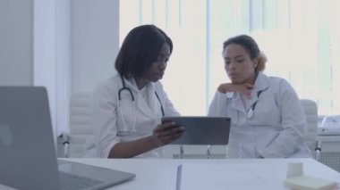 Kalifiye doktorlar hastanın test sonuçlarını tartışıyor, tablet tutuyor, işbirliği yapıyor.