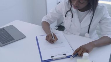 Doktor ilaç reçetesi yazıyor. Belgede, hastalığın tedavisinde.