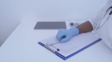 Klinik uzmanı hasta kartı yazıyor, alnına ateş ölçüyor, check-up yaptırıyor.