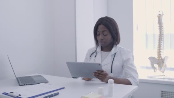 Médico de la clínica llenando documentos en línea, aplicación tableta de desplazamiento, tecnología moderna — Vídeos de Stock