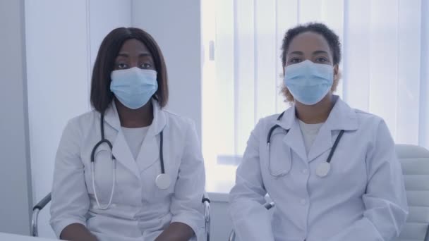 Dos médicas con máscaras mirando a la cámara, enfermedades infecciosas, trabajo en equipo — Vídeo de stock