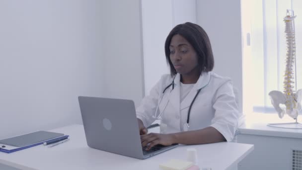 Médica que sofre de dor de cabeça, trabalhando no laptop no escritório, saúde — Vídeo de Stock