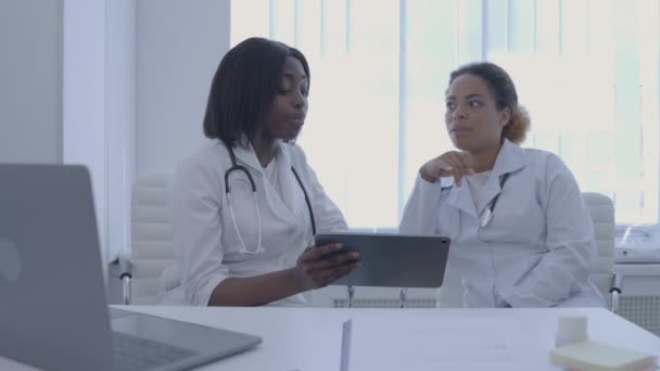 Médico africano mostrando aplicación médica en tableta a colega, consilium — Vídeo de stock