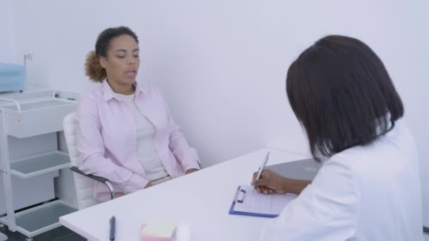 Paciente conversando com médico, terapeuta preenchendo cartão do paciente, consulta médica — Vídeo de Stock