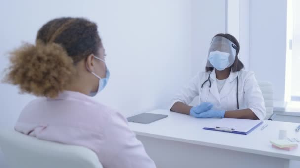 Специалист по защитной маске и защите лица разговаривает с пациентом, вирусом — стоковое видео