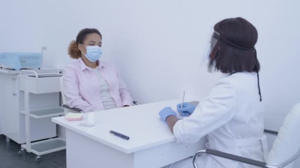戴口罩的年轻妇女在医院与医生交谈，与大脑皮层病毒有关，与健康有关 — 图库视频影像